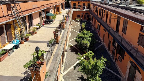 Une cour avec des sièges en plein air, des plantes en pot et un ciel dégagé.