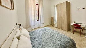 Une chambre à coucher avec un lit, un bureau, une chaise et une armoire.