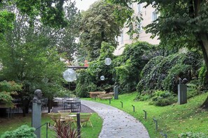 Un jardí amb un camí pavimentat, mobiliari exterior i escultures.