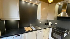 Cocina compacta con lavadora Bosch, un lavabo, estufa y armarios blancos.