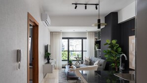 Ein modernes Wohnzimmer mit einer Couch, einem Couchtisch und einem Essbereich mit schwarzer Arbeitsplatte und Spüle.