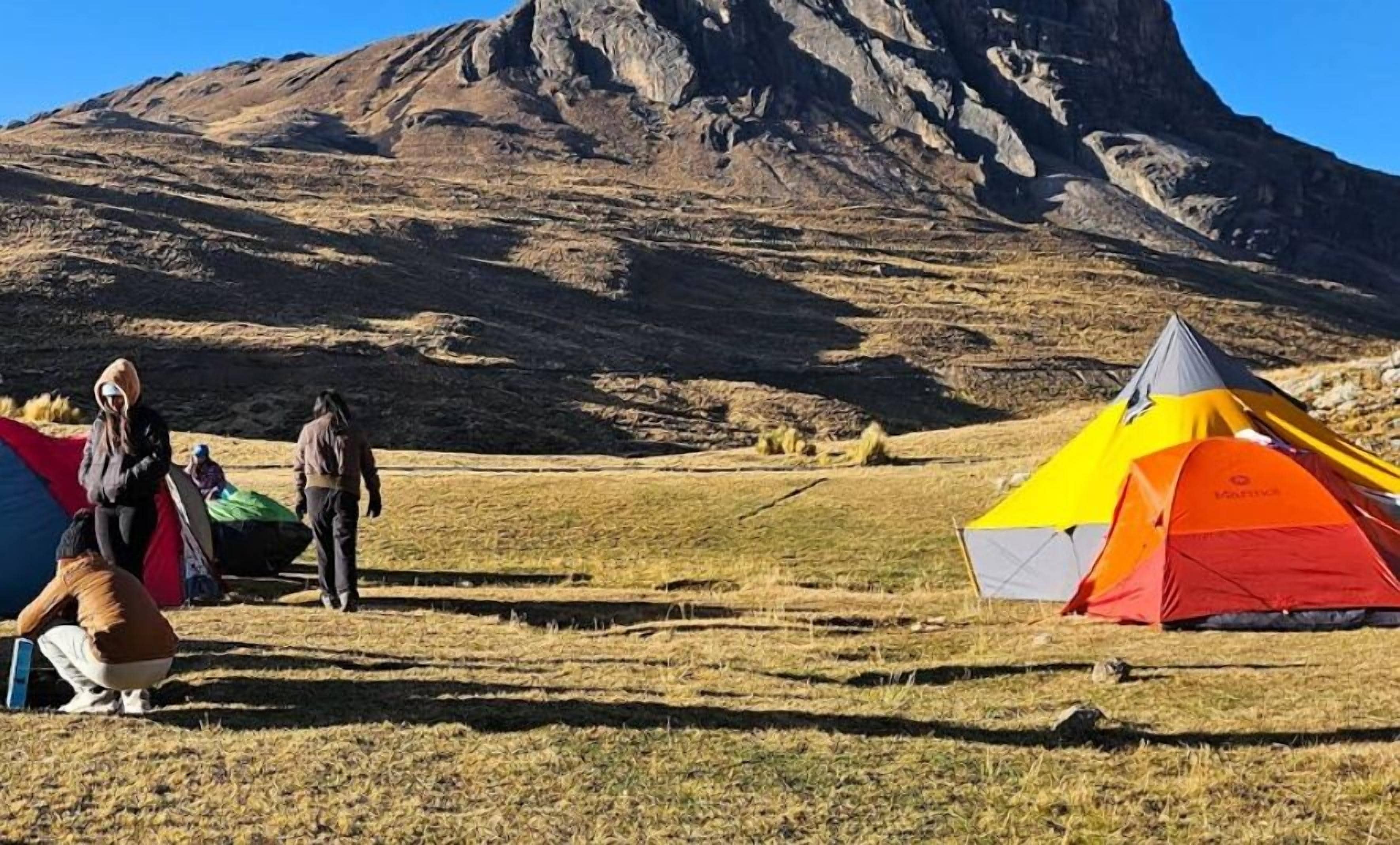 A tent set up in a grassy field with a mountainous backdrop.