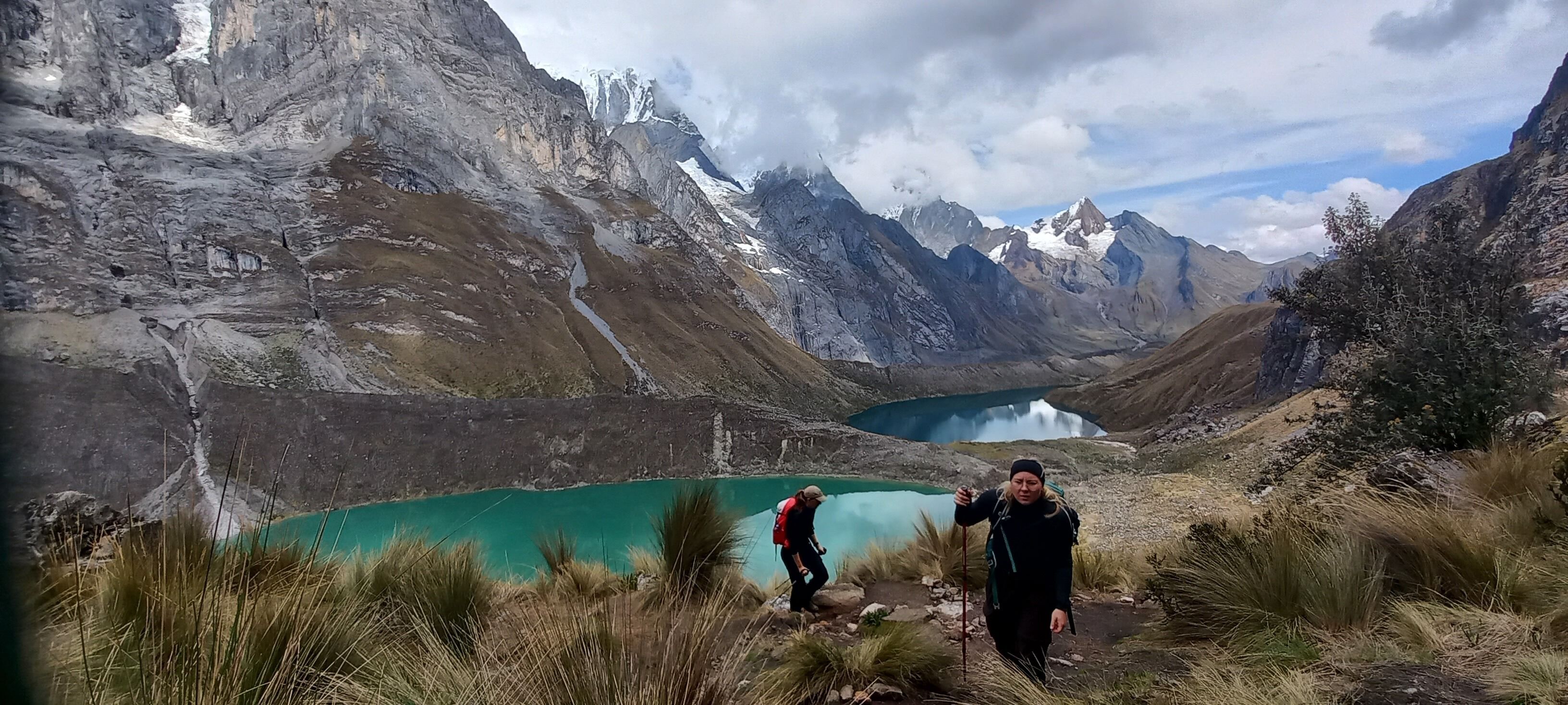 A mountainous landscape with a turquoise lake and hikers.