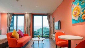 A modern hotel room with a large window, a sofa, a dining table, and a TV. - Flamingo Bau Abtel (Hoang Tien)