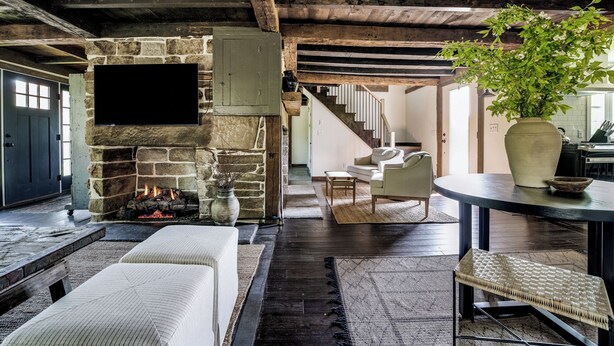 A rustic interior with a stone fireplace, a wooden ceiling, and a cozy seating area with a table and chairs. - The Farmhouse Stay (Haddam)