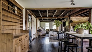 A rustic interior with wooden shelves, a stone fireplace, and a dining area with stools. - The Farmhouse Stay (Haddam)