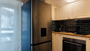 A modern kitchen with a stainless steel refrigerator, a built-in oven, and a black tiled backsplash. - Green Dream: proximity Paris & Disneyland (Villiers-sur-Marne)