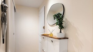 A narrow hallway with wooden flooring, a white wall, and a white cabinet with drawers and a mirror. - Green Dream: proximity Paris & Disneyland (Villiers-sur-Marne)