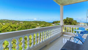 A balcony with a white balustrade, a table, and blue chairs.
