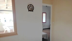 A room with a bed, a small table, and a window. There is a door leading to another room. - Sea view cool apartment with a balcony (Le Barcarès)