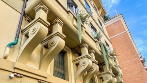 Ein Gebäude mit aufwendigen architektonischen Details, darunter dekorative Säulen und ein Balkon mit hängenden Pflanzen.