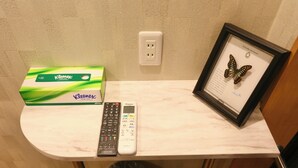 A bathroom with a marble countertop, a Kleenex box, a remote control, and a framed butterfly picture.