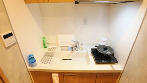 A compact kitchen with a sink, a coffee maker, and a rice cooker on the countertop.