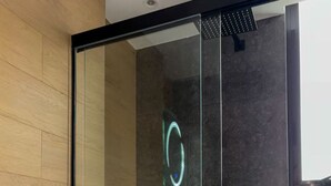 Et moderne badeværelse med en glasbrusekabine, toilet og håndvask.