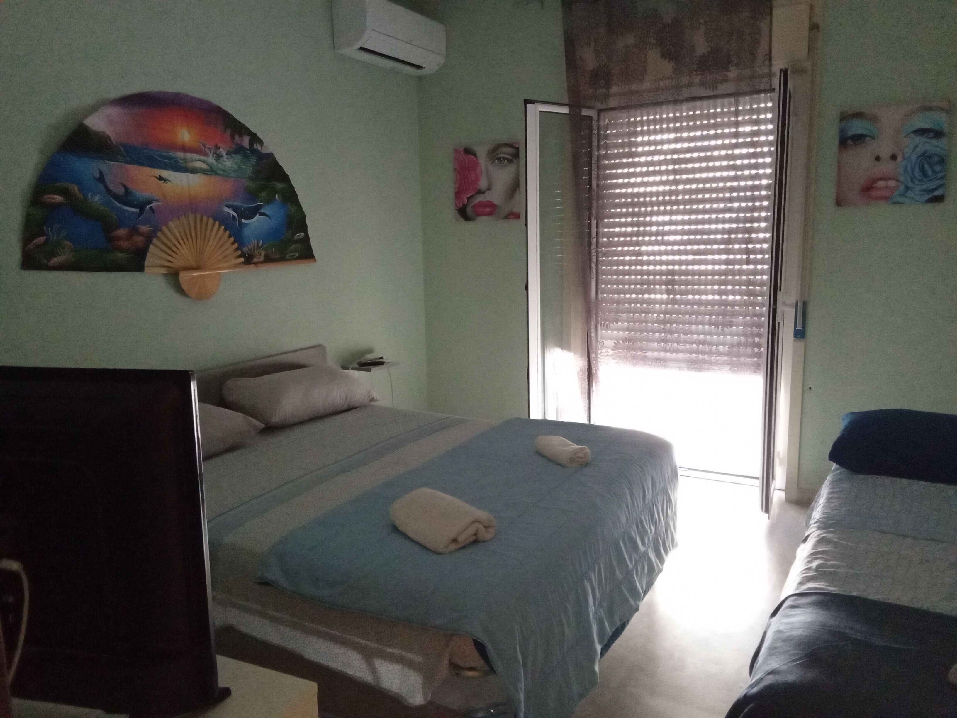 Une chambre à coucher avec un lit, une télévision, un tableau et une fenêtre avec des stores.