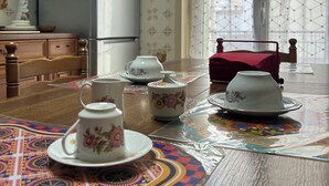 Una cuina amb nevera, armaris de fusta i taula de menjador amb teieres i tasses.