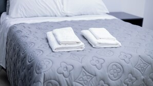 A neatly made bed with a patterned bedspread and two folded towels on the side. - Tranquil, Secure Haven in the Heart of Harare. (Harare)