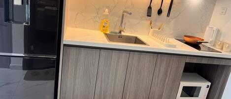 A modern kitchen with a built-in microwave, stainless steel sink, and wooden cabinets.