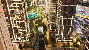Un edificio residencial de gran altura con varios balcones, un patio central con piscina y una calle bien iluminada.
