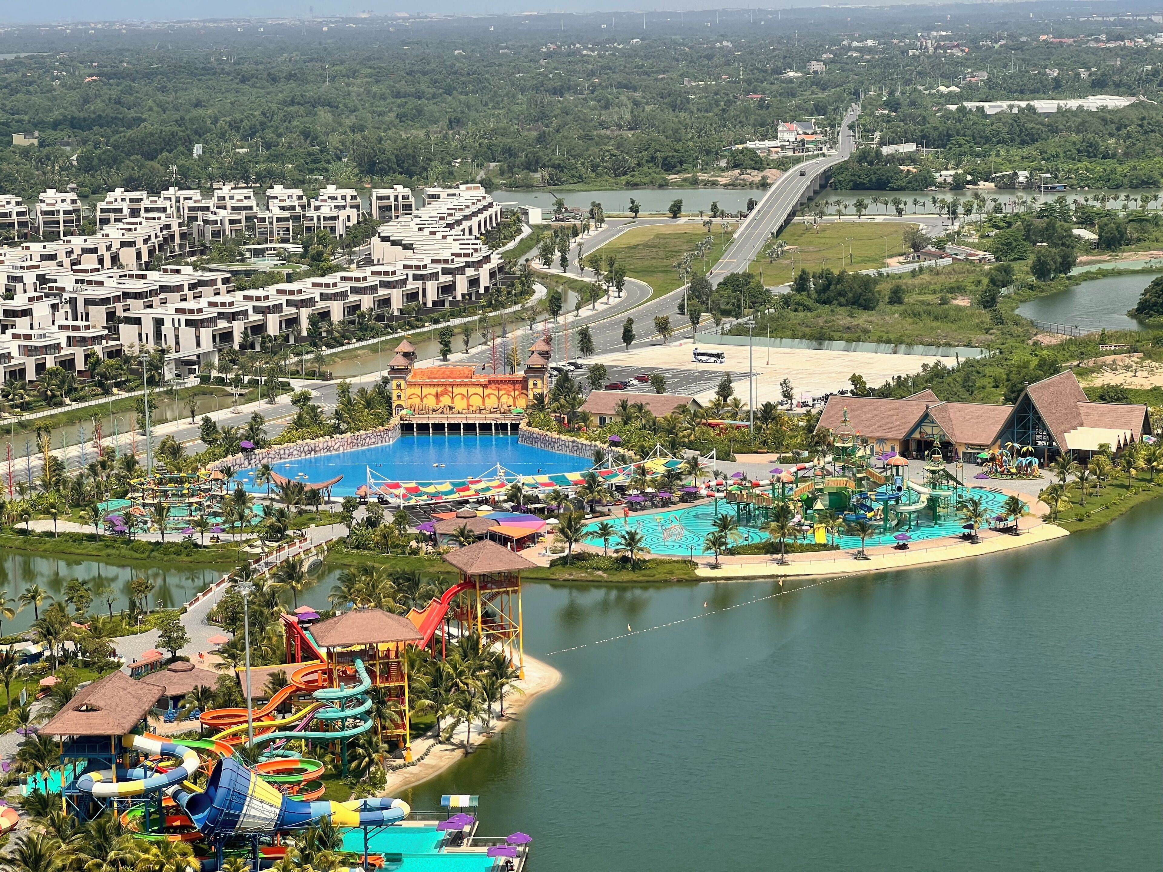 A resort with a large pool, water park, and a bridge over a river.