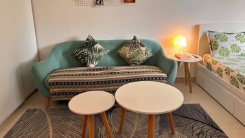 Un salon chaleureux avec un canapé de couleur turquoise, des coussins à motifs, une table basse et un mur décoré de photos.