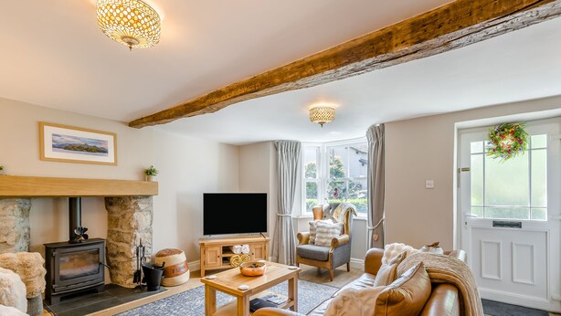 A cozy living room with a fireplace, a television, a comfortable sofa, and a dining table.