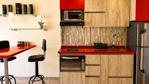 Une cuisine moderne avec des meubles en bois, un plan de travail rouge, un réfrigérateur en acier inoxydable et un four à micro-ondes.