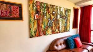Ein Wohnzimmer mit braunem Ledersofa, einem Glastisch und einem großen abstrakten Gemälde an der Wand.