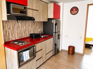 Une cuisine avec un plan de travail rouge, des appareils en acier inoxydable et des armoires en bois.