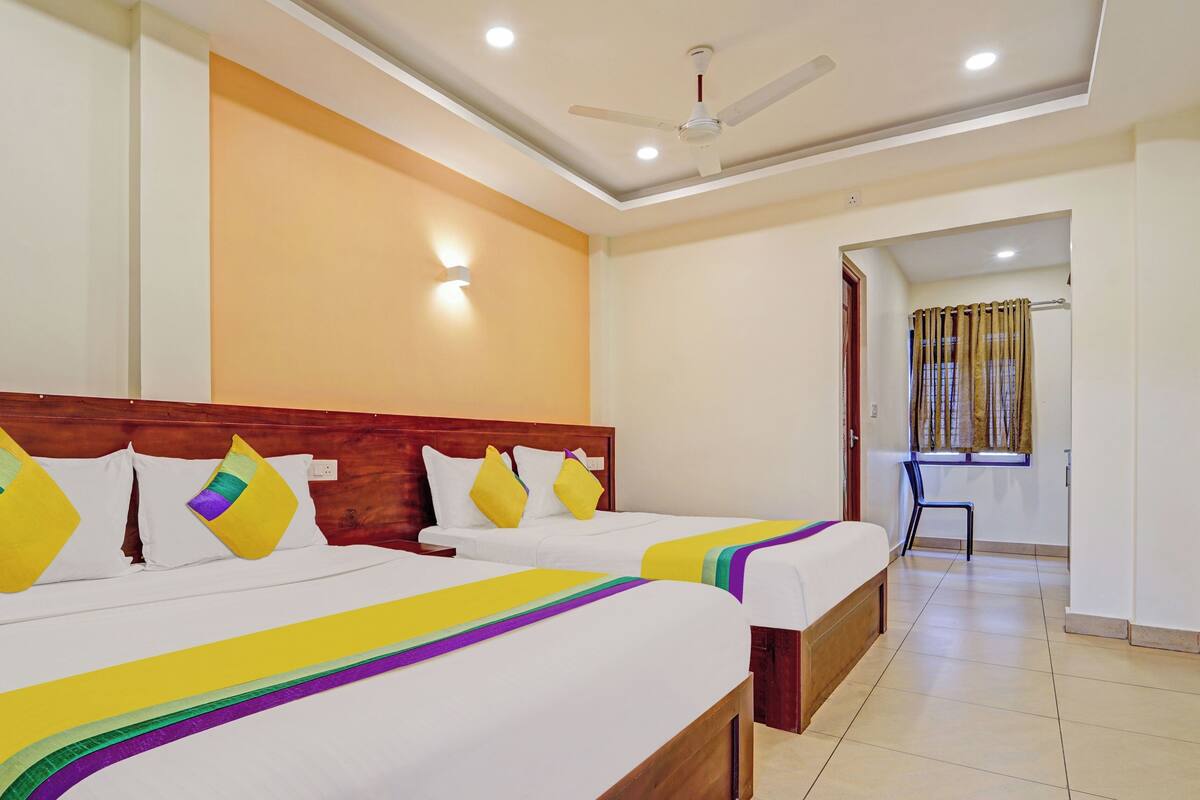 A hotel room with two beds, a ceiling fan, and a bathroom visible through an open door.