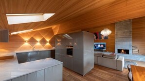 A modern kitchen with a central island, built-in appliances, and a dining area with a sofa and table. - Chalet RoyAlp Hotel and Spa (Ollon)