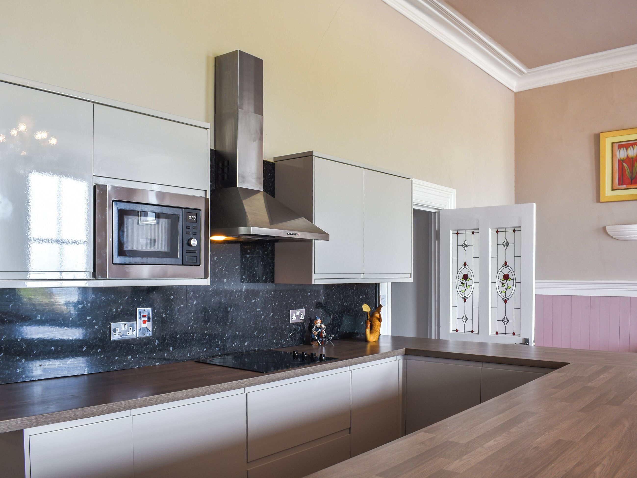 A modern kitchen with stainless steel appliances, a black granite countertop, and a recessed cooktop.