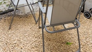 A small outdoor patio with a round table, four chairs, and a grey umbrella. There are potted plants on the table and a sign that reads "GARDEN" on the wall. - Cozy Flat in the Heart of Camden (Greater London)