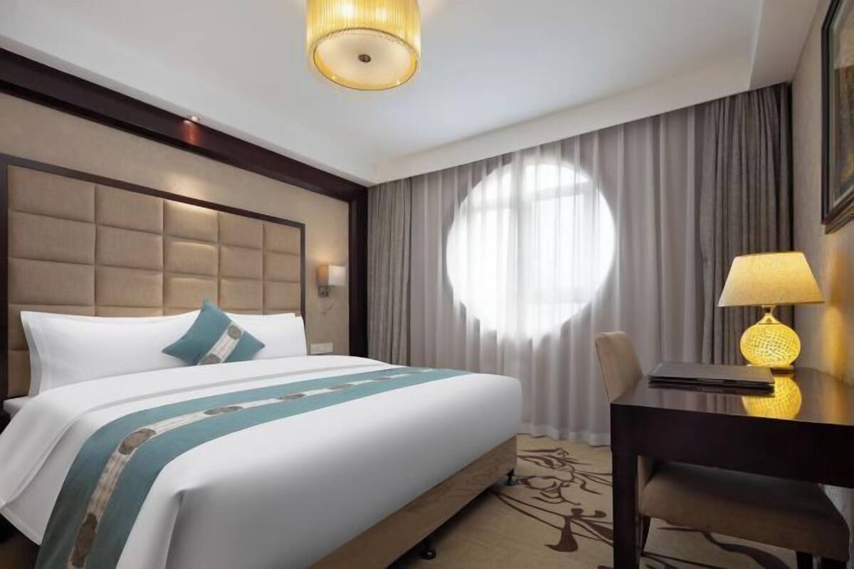 A hotel room with a large bed, a desk, and a chair.