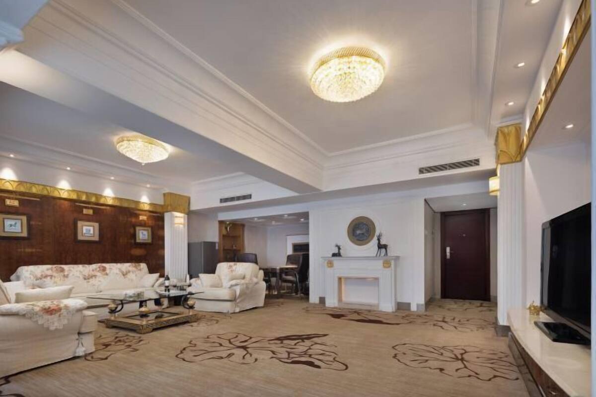 A spacious living room with a fireplace, a television, and a chandelier.