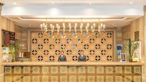 Una recepción con una pared decorativa, dos recepcionistas y un candelabro.