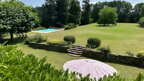 A well-maintained lawn with a swimming pool, stone walls, and a large umbrella. - Le Pigeonnier du Bordial (Molières)