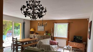 A cozy living room with a green sofa, wooden dining table, and a chandelier. - Vacation home in the heart of Provence (Eyragues)