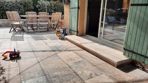 A patio with a table and chairs, a toy truck, and a green door. - Vacation home in the heart of Provence (Eyragues)