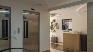 A hotel lobby with a reception desk, a potted plant, and an elevator. - Cozy 2 Bedroom Apartment in the center of Camboriú, 200 meters from the beach (Centro Balneário Camboriú)