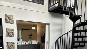 Ein Schlafzimmer mit Bett, einer Treppe und einem durch eine geöffnete Tür einsehbaren Badezimmer.