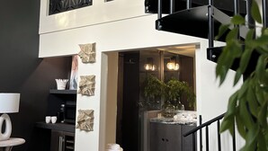 Ein modernes Interieur mit einer Treppe, einer Küchenzeile und einer Sitzecke mit Lampe und Kissen.