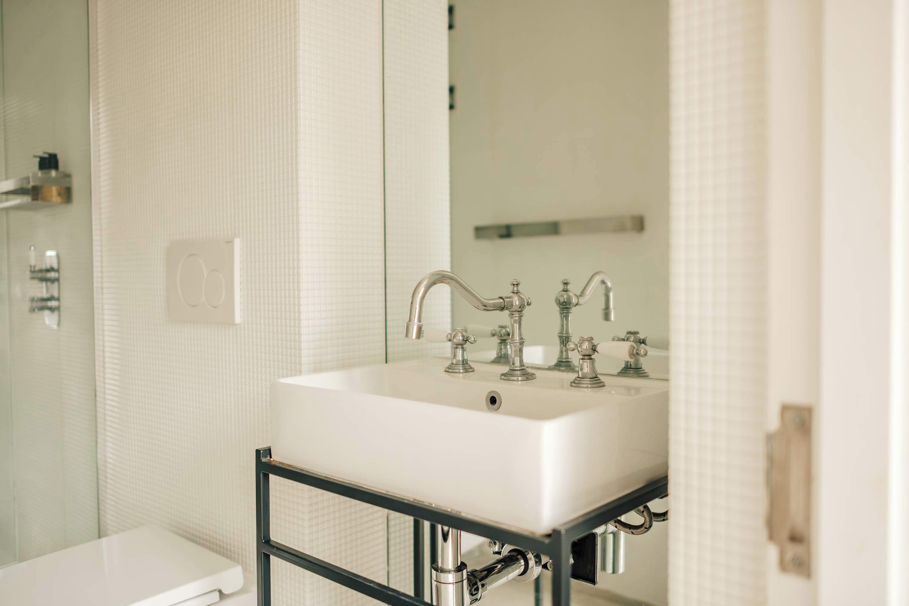 Un bagno con lavandino bianco, uno specchio e zona doccia.