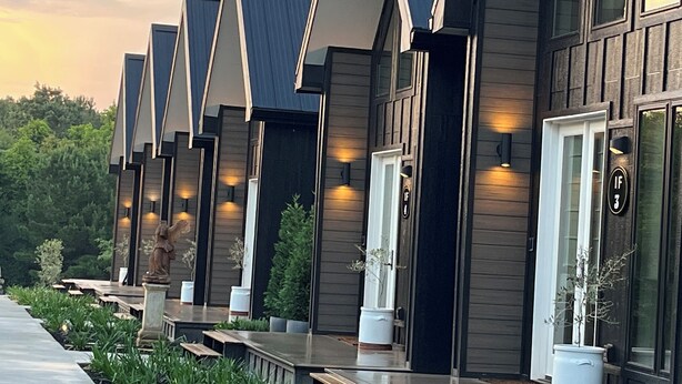 Una hilera de edificios modernos de color oscuro con techos inclinados y grandes ventanales, probablemente parte de un hotel o resort.
