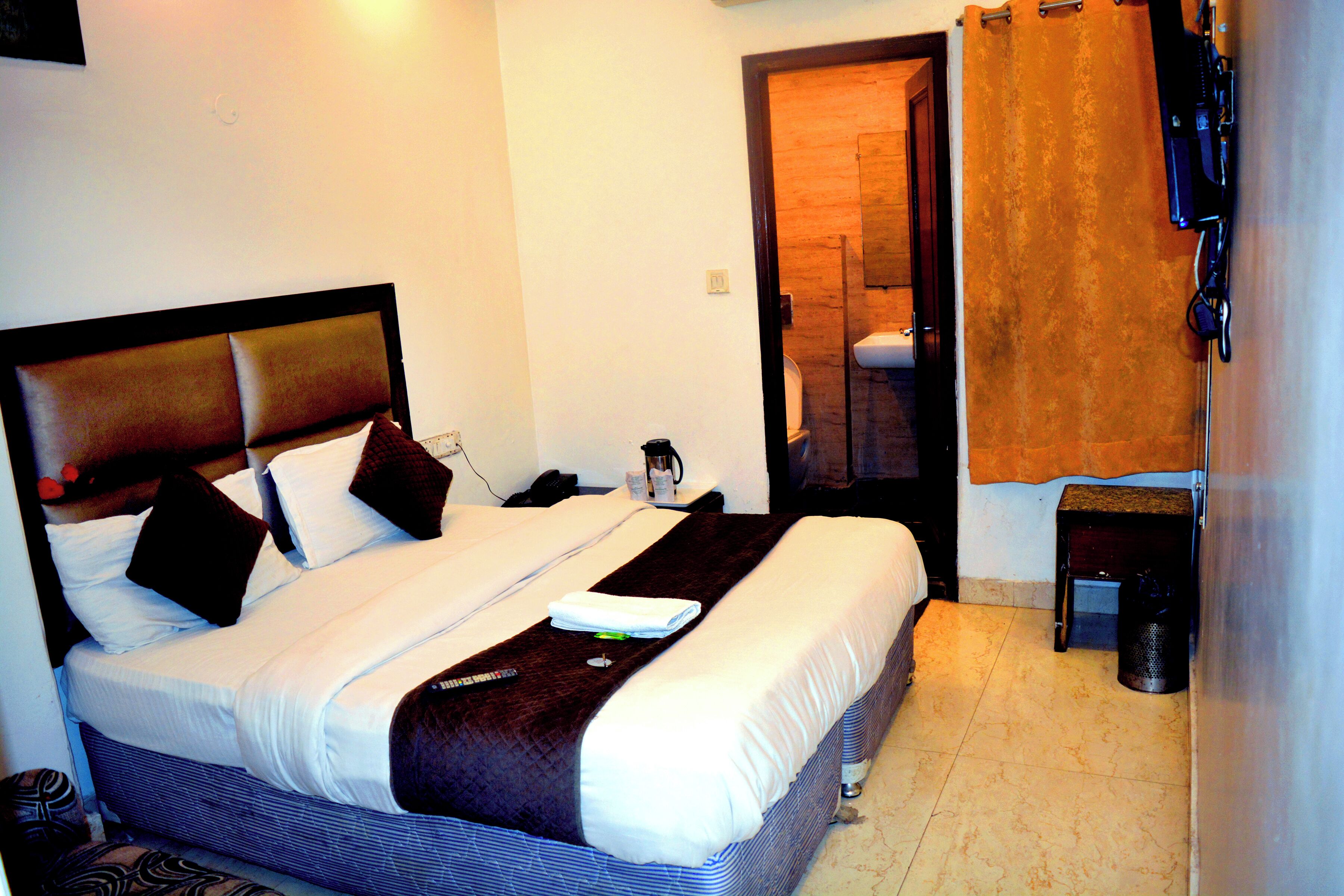 Una habitación de hotel con una cama grande, una mesita de noche, una pequeña mesa, una silla, un espejo y una puerta.