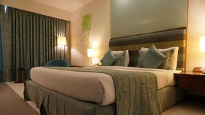 Una habitación de hotel con una cama grande, una silla, una mesita de noche y una lámpara.