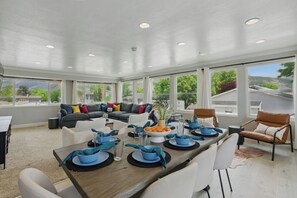 A spacious living room with a dining area, large windows, and a view of the outdoors. - 1 min from Lindon Temple- Hot tub, Sleeps 16, Xbox, Poker, 6 Bed (Orem)