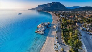 An aerial view of a coastal town with a marina, clear blue waters, and a prominent mountain in the background. - Le Sicilien - Villa Harmony - Relax in Mondello (Palermo)