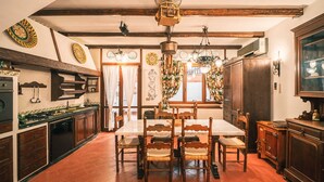 A traditional kitchen with wooden beams, a dining table with chairs, and a large window with curtains. - Le Sicilien - Villa Harmony - Relax in Mondello (Palermo)