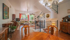 Ein geräumiger Wohnbereich mit Treppe, Holzmöbeln und einer Chandelüster.